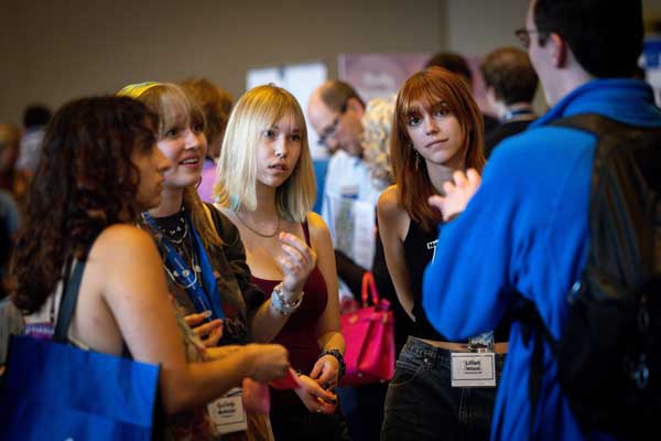 Five students in conversation in a crowd-filled room