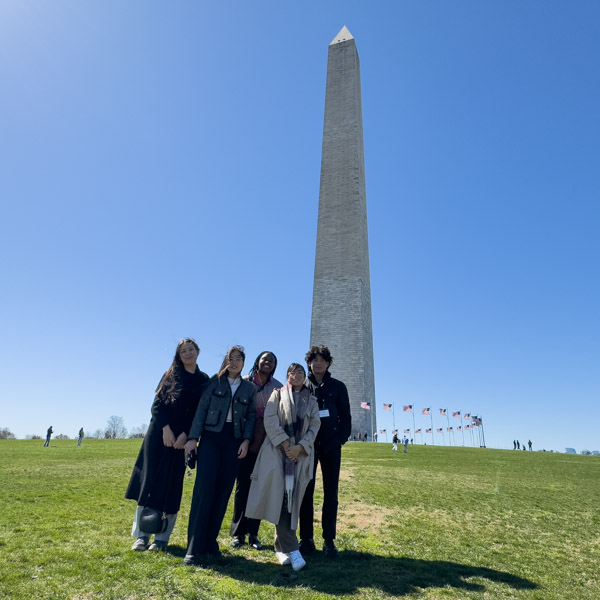 A group of students poses with the Washington Monument in the background.