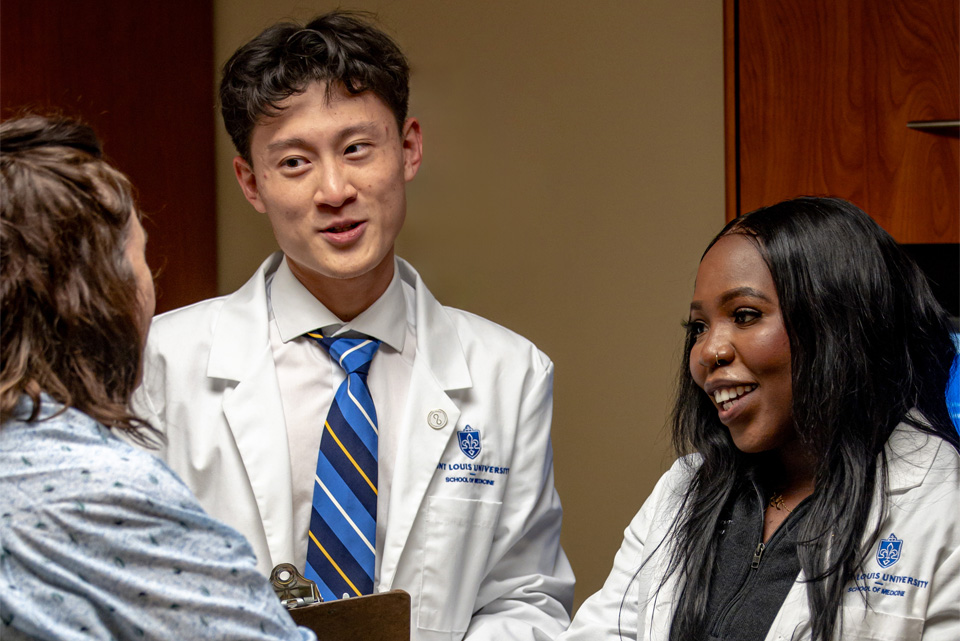 Two students talking with a standardized patient at the clinical skills center