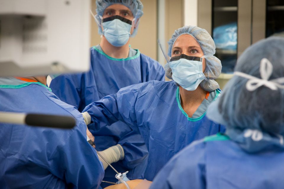 Medical professionals in surgical scrubs performing a procedures in an operating room