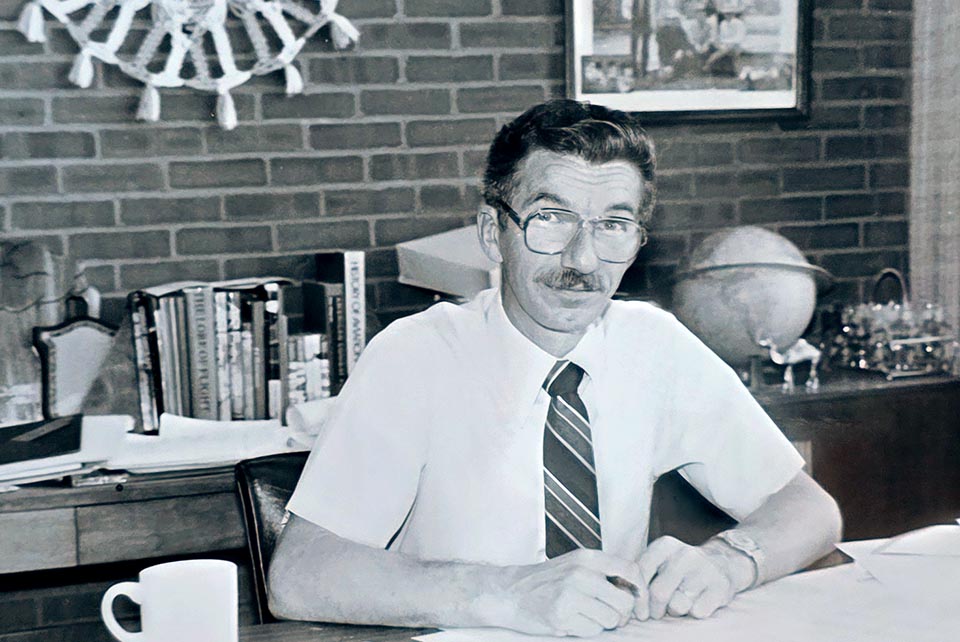 a man sits at a desk in black and white photo