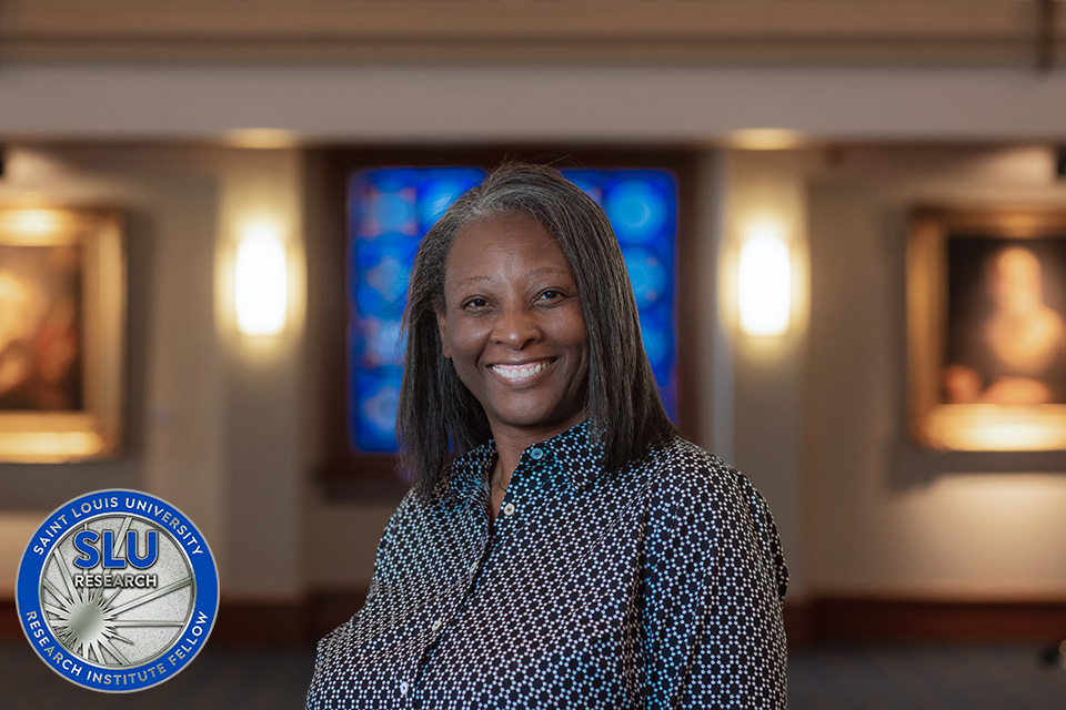 Christa Jackson, Ph.D., with a coin that says SLU Research Institute Fellow